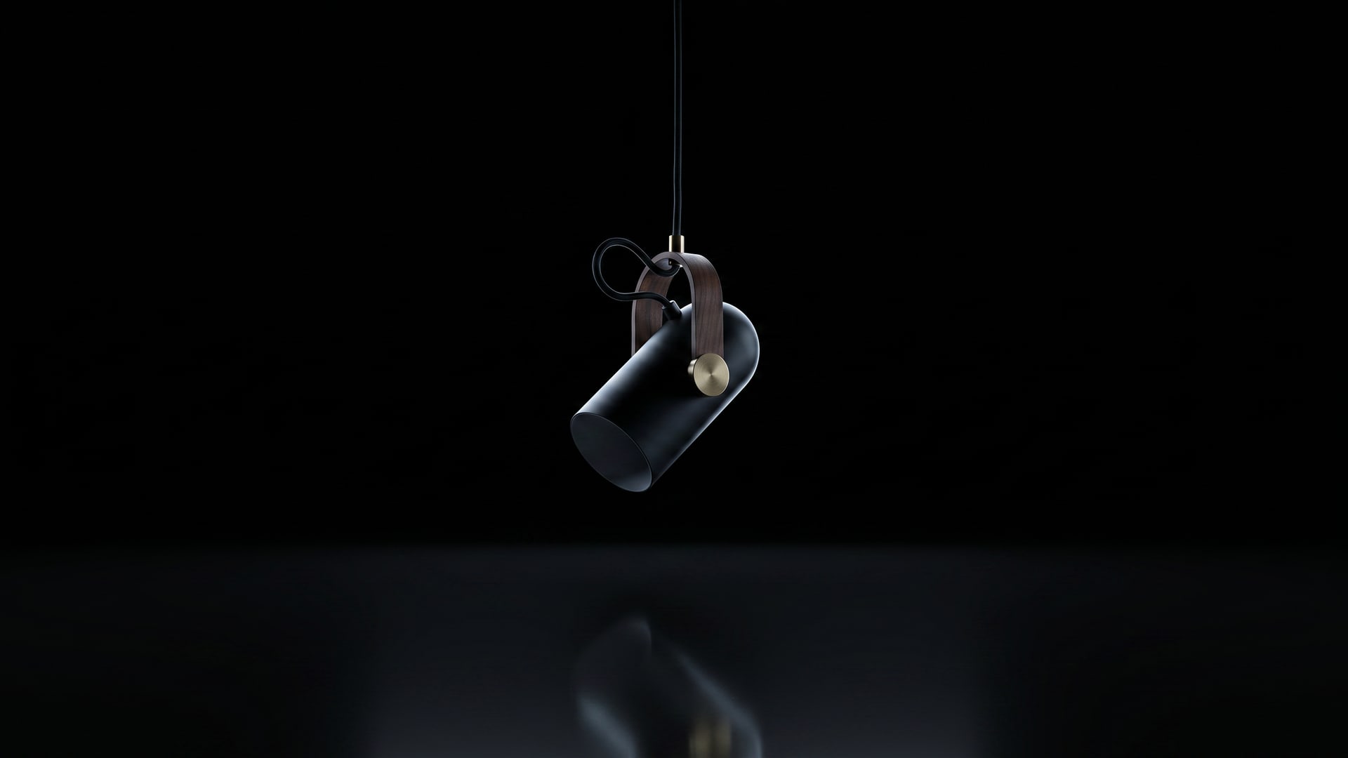 The Tilt pendant suspended unlit in a black void, faint reflection below